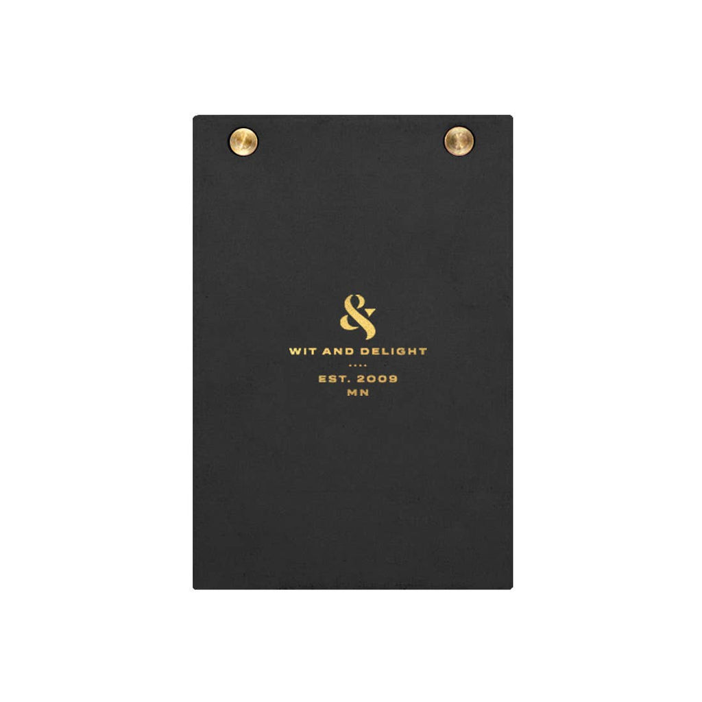 A black textured clipboard with gold metal grommets at the top and gold foil branding for 'Wit and Delight' in the center, shown on a plain white background.