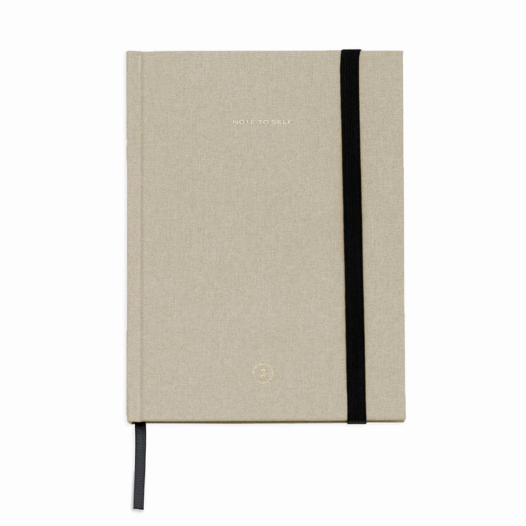 A hardcover notebook with a textured beige linen cover, featuring a black elastic closure band and a matching black ribbon bookmark, shown on a plain white background.