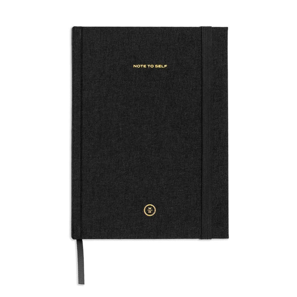 A black textured hardcover notebook with gold foil lettering that reads 'NOTE TO SELF' and a small circular gold logo near the bottom, shown on a plain white background.