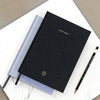Black notebook with 'Note to Self' text on a marble surface with a pencil.