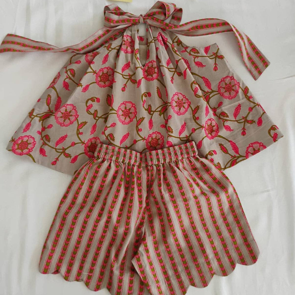 A children's two-piece outfit laid flat on a white fabric background, featuring a sleeveless top with a pink floral print on a beige base and matching striped tie straps, paired with striped shorts. A yellow tag reading 'JUMPMAN' is attached at the top.